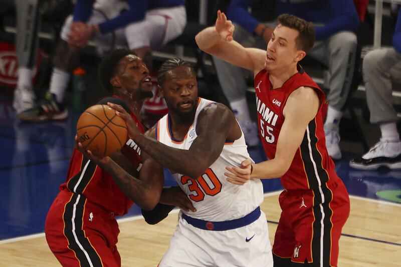 The New York Knicks' Dennis Smith Jr., dunks over the Miami Heat's